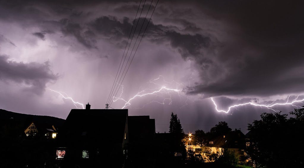 Silhouette of houses against a vivid lightning storm in Schwäbisch Gmünd, Germany.