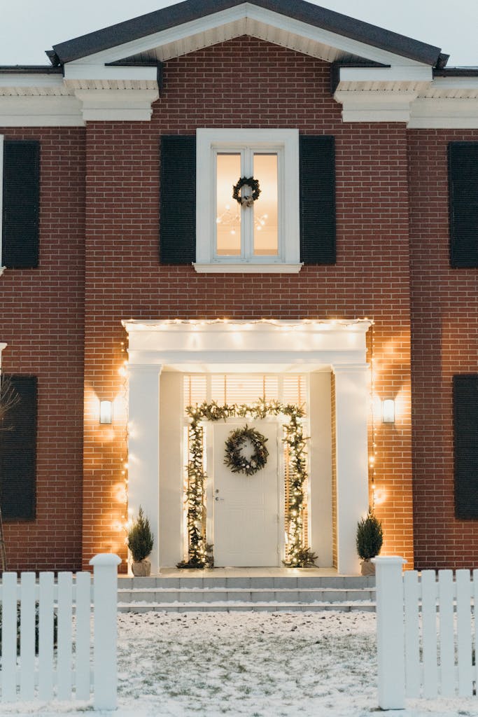 Charming brick house with festive Christmas wreath and lights, perfect for holiday atmosphere.