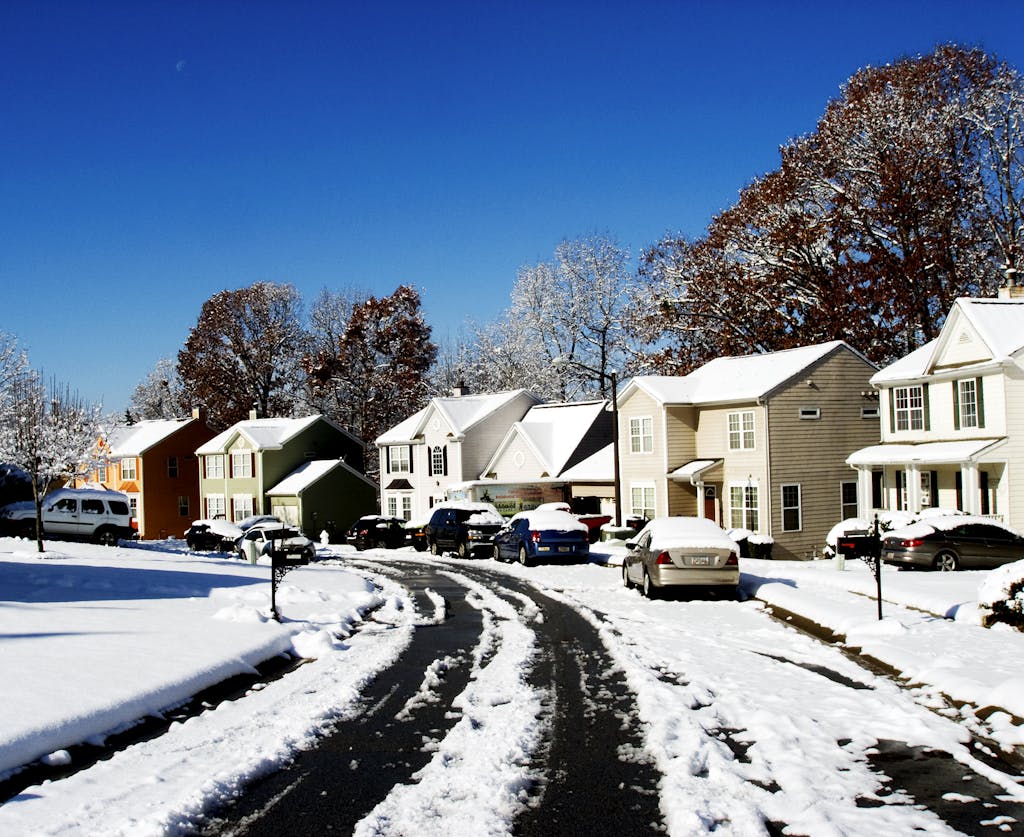 A picturesque snowy street view in Austell, Georgia with colorful houses and a clear blue sky.
