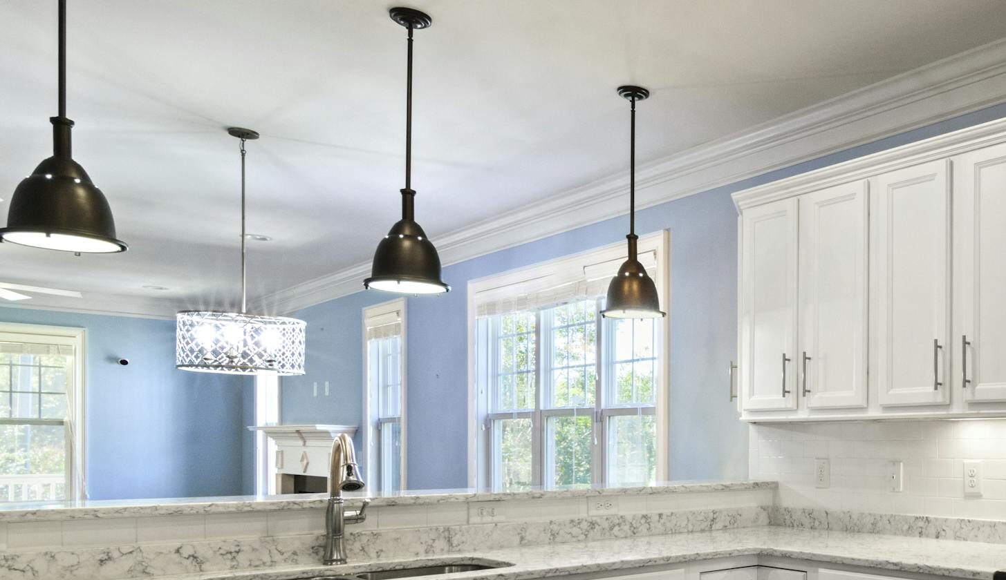 A bright, spacious kitchen with marble countertops, stainless steel appliances, and elegant white cabinetry.